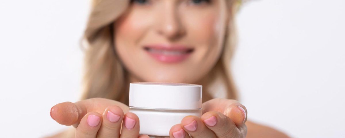 Cremă pentru buze crăpate, ținută in mâna de o femeie.