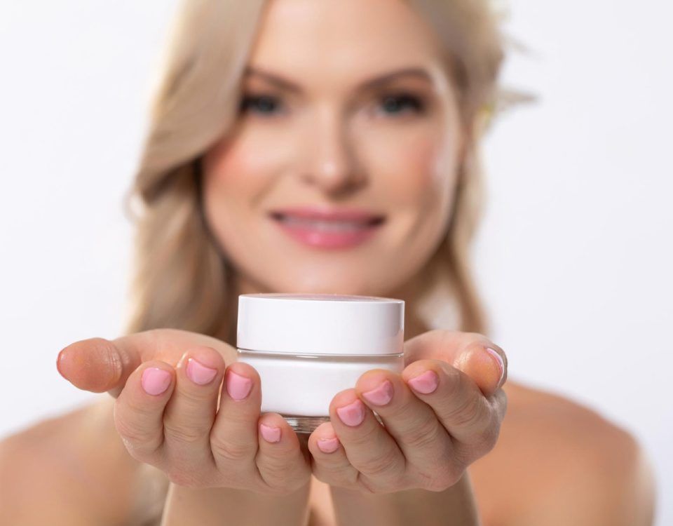 Cremă pentru buze crăpate, ținută in mâna de o femeie.